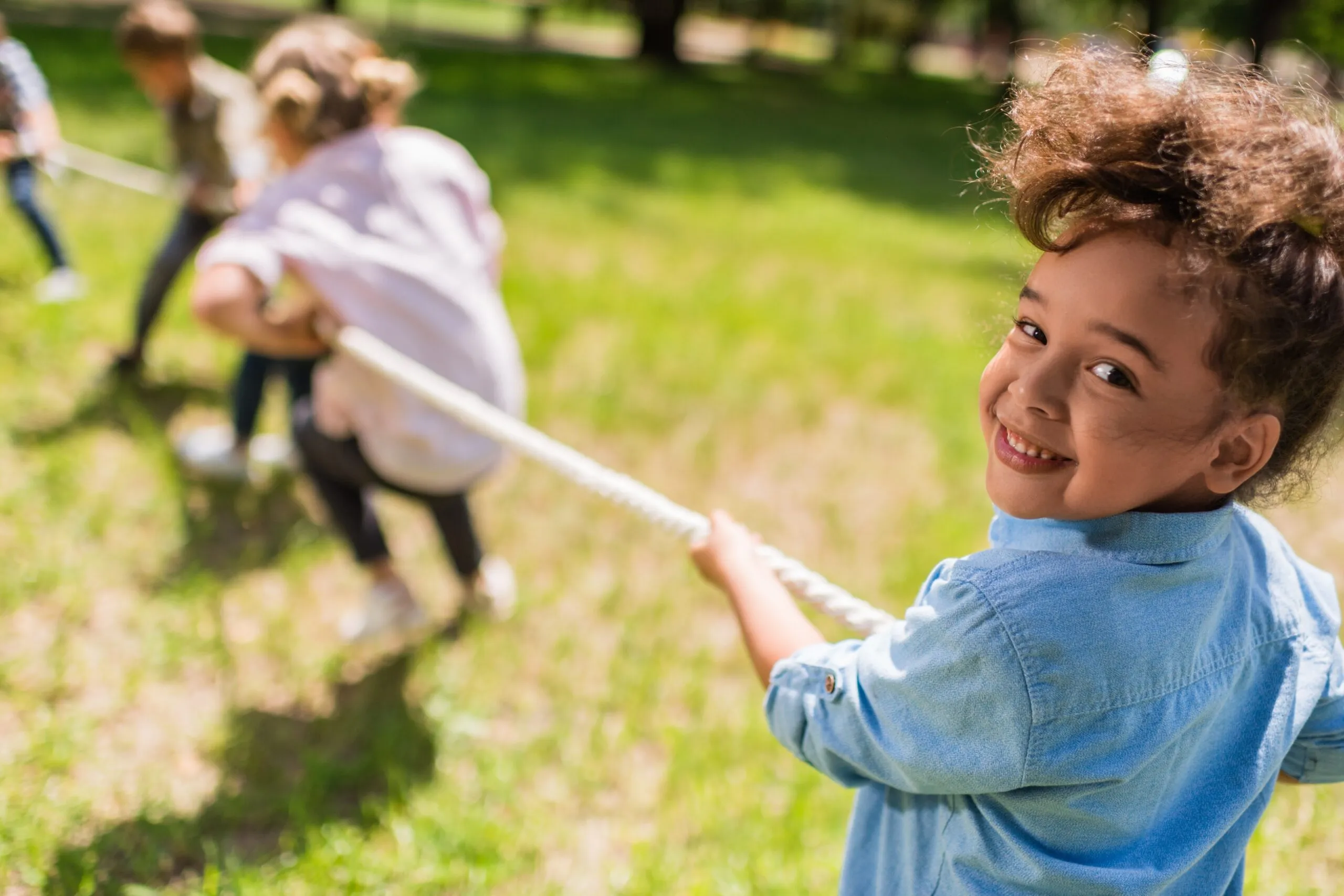 Kleuters die aan het touwtrekken zijn op een grasveld op een zonnige dag