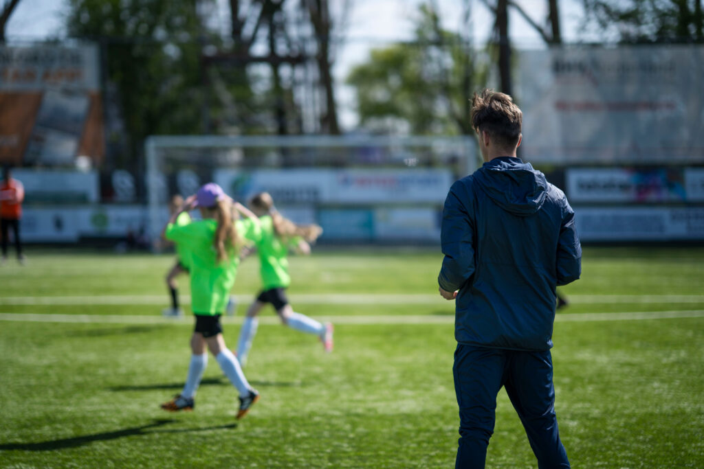 Een coach die training geeft aan basisschool kinderen op een sportveld