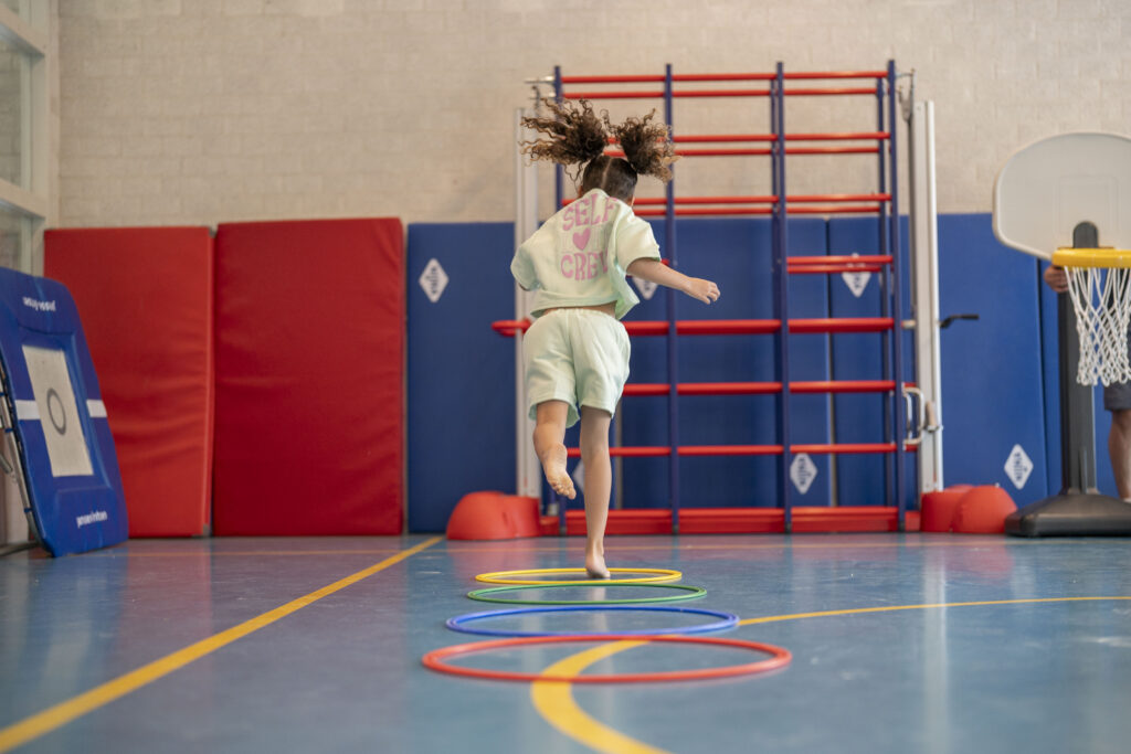 Meisje dat aan het hinkelen is in een gymzaal