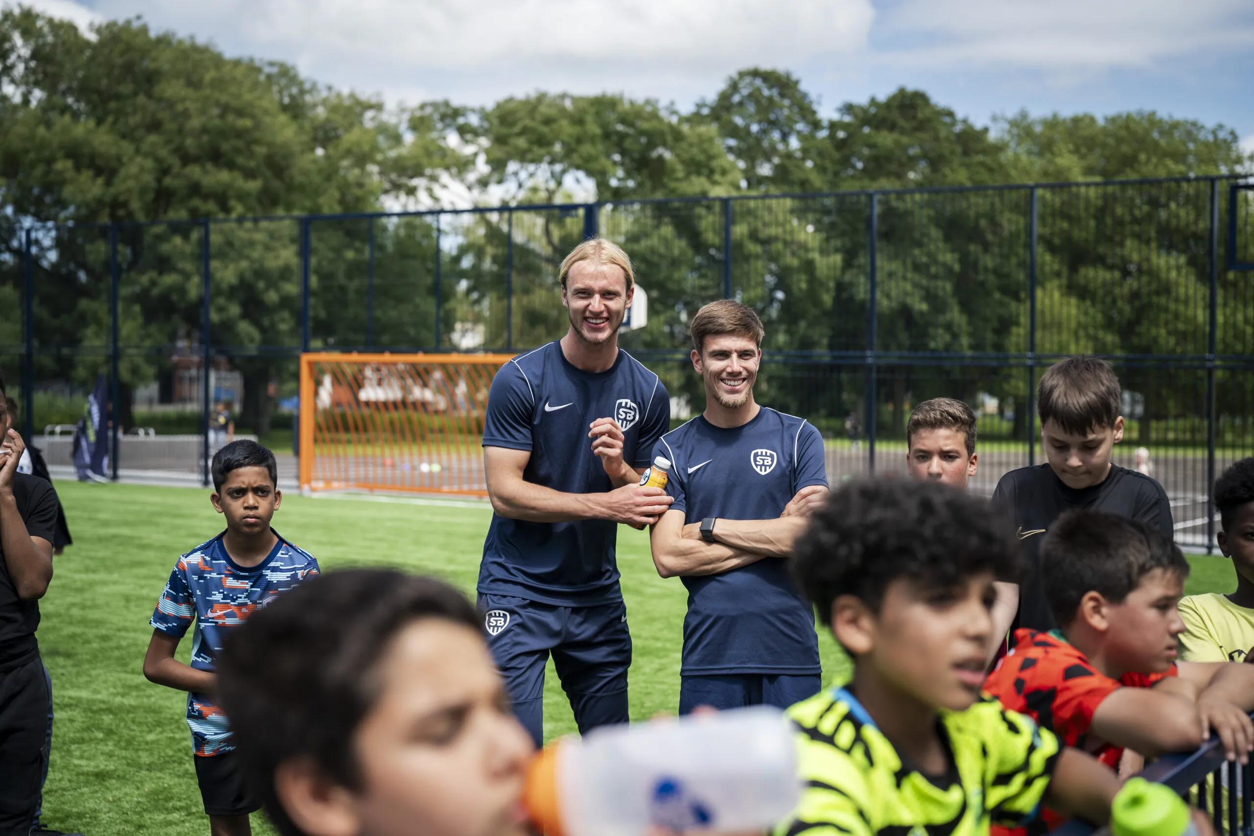 Twee trainers op een voetbalveld met jongeren