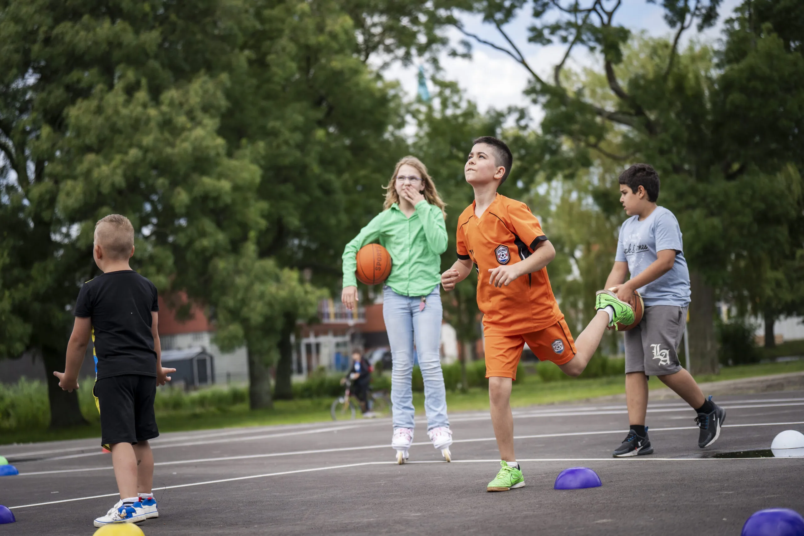 Kinderen die op een speelveldje aan het basketballen zijn