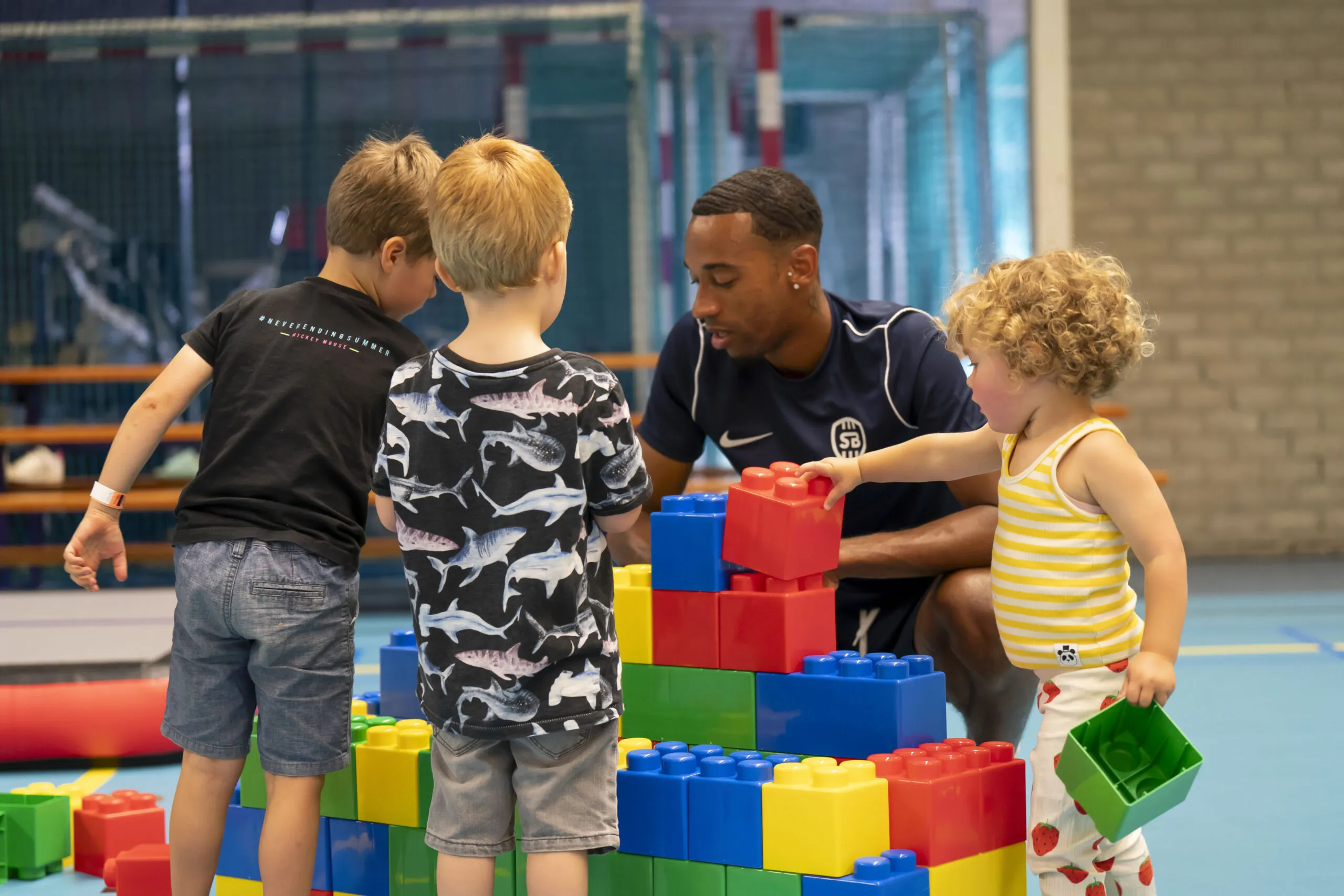 Trainer die tijdens de peutergym iets uitlegt aan de kinderen